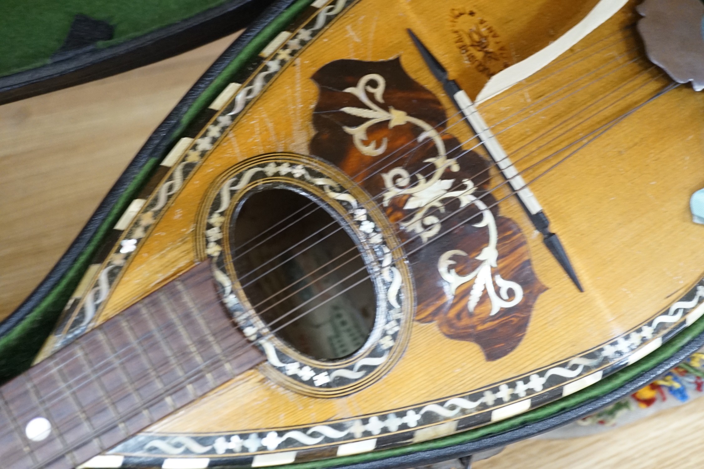 A cased late 19th/early 20th century Italian lute back mandolin with segmented rosewood back and spruce top, eight brass and bone pegs, 60.5cms high